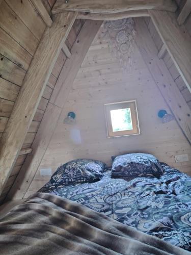 a bed in a wooden room with a window at La chaumière ensorcelée in Anor