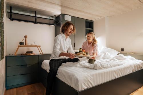 a man and a woman sitting on a bed at Sume by Larsen in Tallinn