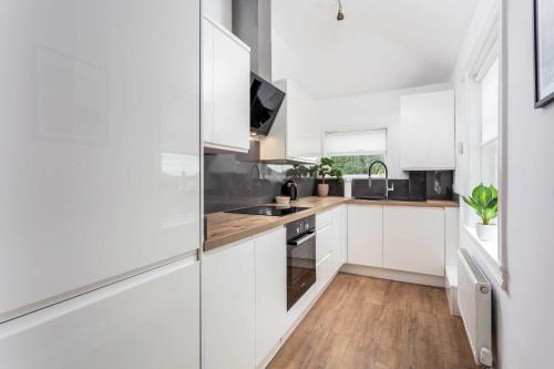 a white kitchen with wooden floors and white cabinets at Scott Suite - Donnini Apartments in Kilmarnock