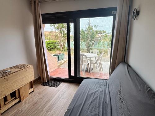 a room with a bed and a table and a patio at 423 Résidence Aphrodite naturiste in Leucate-Plage