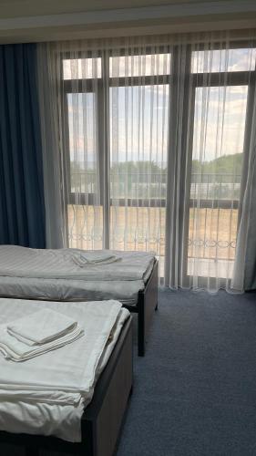 a hotel room with two beds and a large window at Ак-Кеме отель in Bosteri
