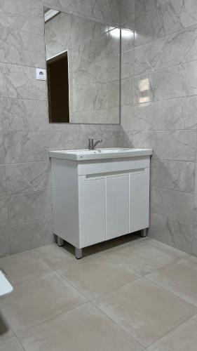 a white bathroom with a sink and a mirror at Ак-Кеме отель in Bosteri