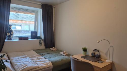 a bedroom with a bed and a desk and a window at Cute Mini Studio in Kristiansand