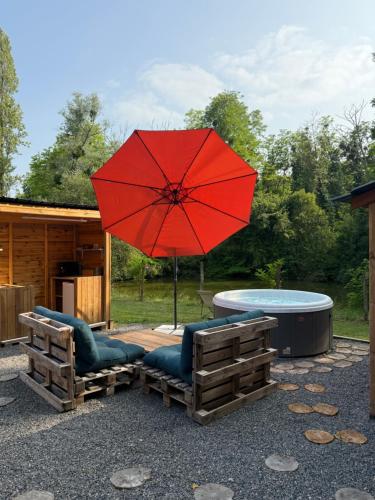 a red umbrella and two chairs and a table at Foudre Insolite in Naujan-et-Postiac