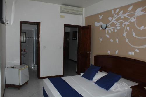 a bedroom with a bed with blue pillows at Residencial Beleza in Mindelo
