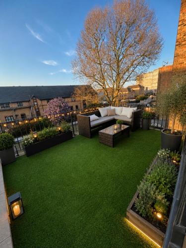 a patio with green grass and a couch on a balcony at Plaza London Hotel in London