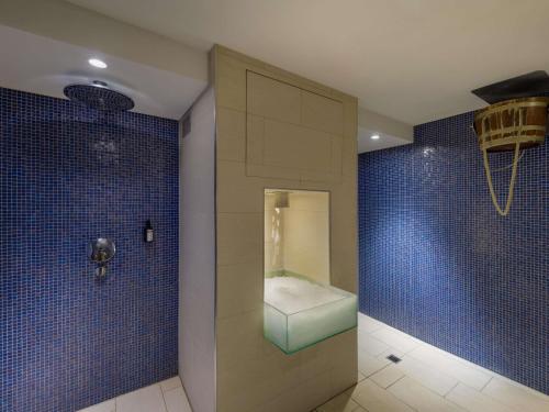 a bathroom with a shower with a bench in it at Mövenpick Hotel Amsterdam City Centre in Amsterdam