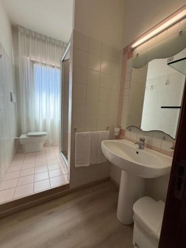 a white bathroom with a sink and a toilet at Hotel Costa Verde in Pineto
