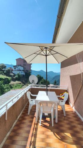 a white table and chairs on a balcony with an umbrella at Uscio Natura in Uscio