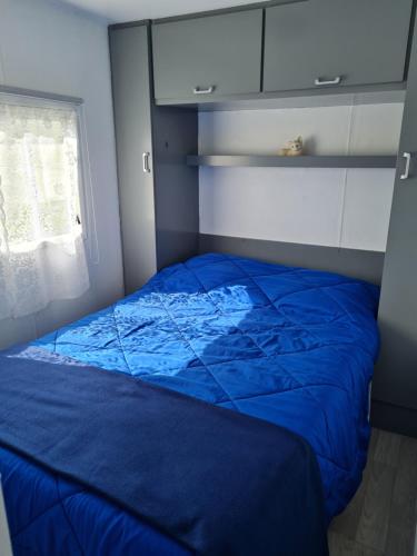a blue bed in a room with a window at Mobilhome empl 28 in Saint-Martin-aux-Buneaux