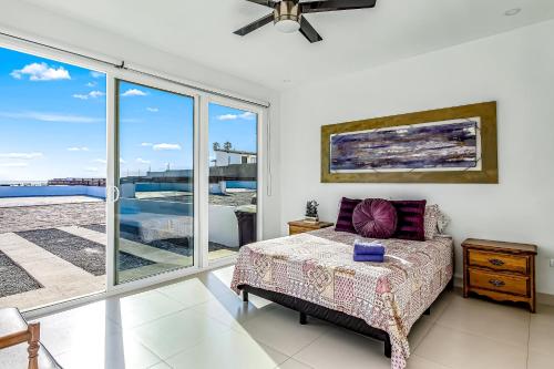a bedroom with a bed and a large window at Dog-Friendly Oceanfront Villa with Rooftop Patio, Pool Access, & Kitchen in Rosarito