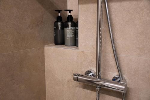 two black shampoo bottles sitting on a shelf in a shower at Alpine Escape 1BR Apartment A in Tarvisio