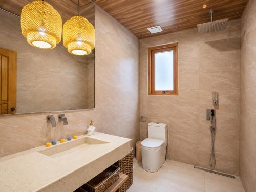a bathroom with a sink and a toilet and a mirror at Palmelía Beach Resort in Buruanga