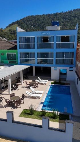 a large building with a swimming pool and tables and chairs at Catamarã Pé na Areia in Angra dos Reis