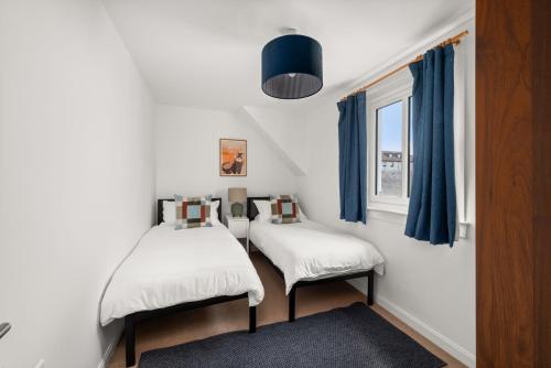 two twin beds in a room with a window at Willow Cottage, North Street in St. Andrews