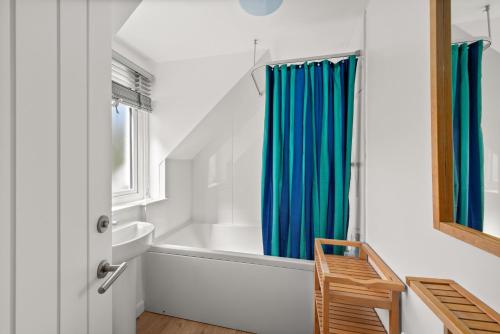 a bathroom with a white tub and a blue shower curtain at Willow Cottage, North Street in St. Andrews