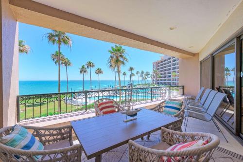 a balcony with a table and chairs and the ocean at Sonoran Spa Amazing Oceanfront E206 in Puerto Peñasco