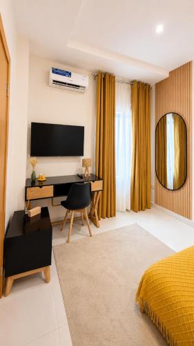 a bedroom with a bed and a desk with a computer at The Luxe Cottage in Ikeja