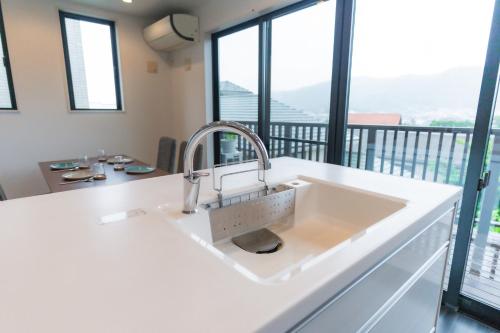 a kitchen with a sink and large windows at SANMI Hayama in Hayama