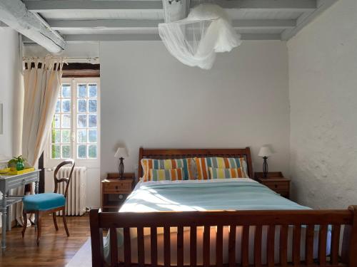 a bedroom with a bed and a desk and a window at La Bordeneuve - Chambre d'hôtes in Auch
