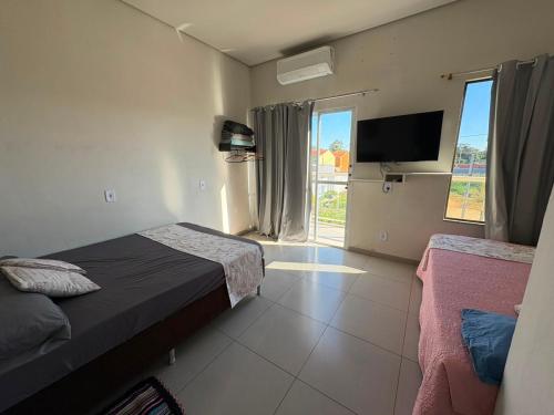 a bedroom with a bed and a tv and a window at Casa Temporada Aconchego e tranquilidade 2 in Bonito