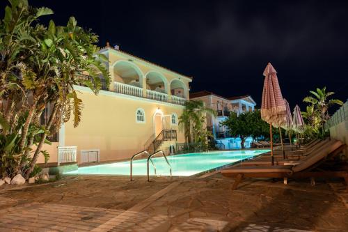 a swimming pool in front of a house at night at California Beach Hotel - Adults Only in Laganas