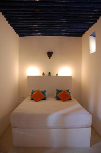 a bedroom with a white bed with orange pillows at Riad Dar Soufa in Rabat