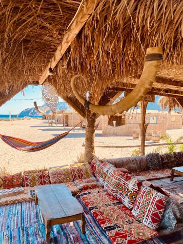 a couch and a hammock under a straw hut on the beach at Galuma magbul camp in Dahab