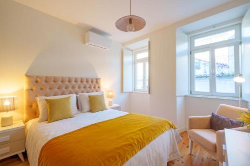 a bedroom with a bed and a chair and windows at Figueirinhas Home Green in Coimbra