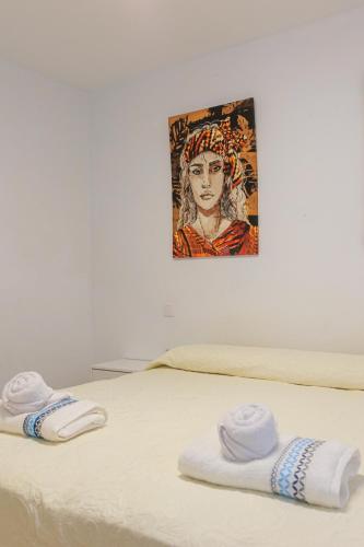 two towels on a bed with a painting on the wall at Blue Río Playa, Casa & Studio in Costa Calma