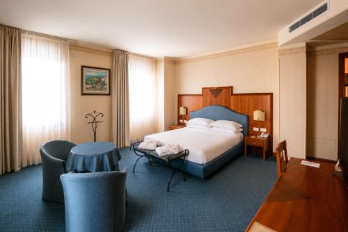 a hotel room with a bed and a table and chairs at Phi Hotel Astoria in Susegana