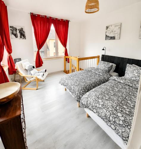 two beds in a bedroom with red curtains at L'échappée Verte en Thiérache in Martigny