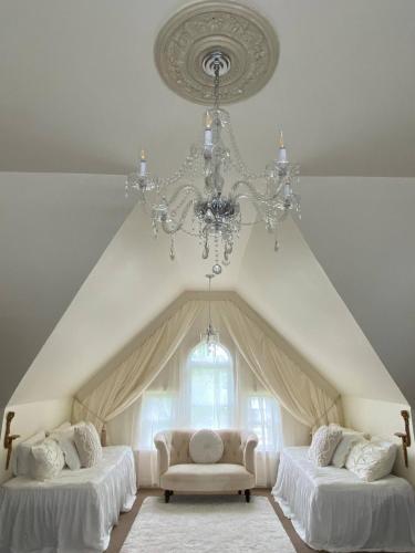 a room with two beds and a chandelier at Four Winds Victorian Venue & Suites in Bonham