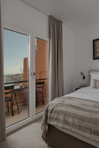 a bedroom with a bed and a balcony with a table at Papi Boutique Hotel in Vathí