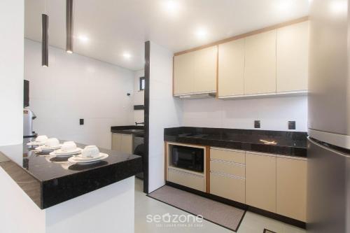 a kitchen with white cabinets and black counter tops at Full stay with pool just 350m from the beach in Porto Seguro | PRY in Porto Seguro