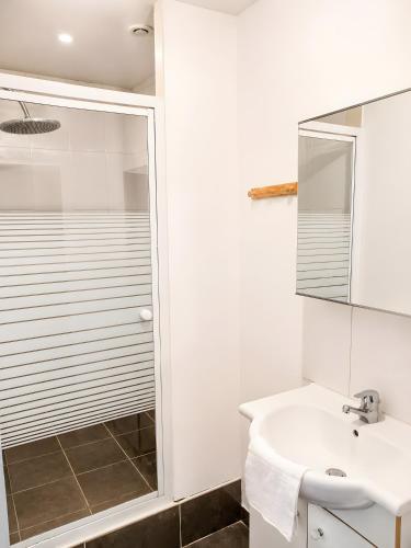 a white bathroom with a shower and a sink at L'échappée Verte en Thiérache in Martigny