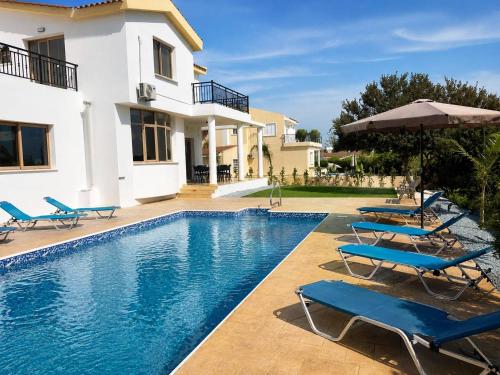 a villa with a swimming pool with chairs and an umbrella at Mariandy Villa 2 in Coral Bay