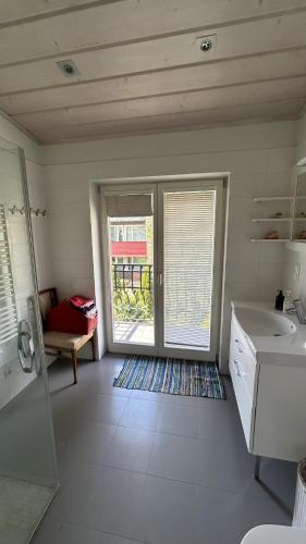 a white bathroom with a sink and a window at Melluzi Seaside Residence in Jūrmala