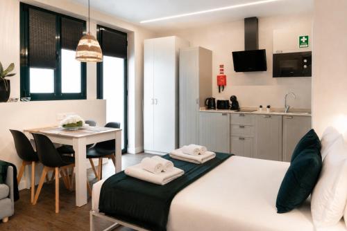 a bedroom with a bed and a table and a kitchen at Social Lodge Cabouqueira Studios in Funchal