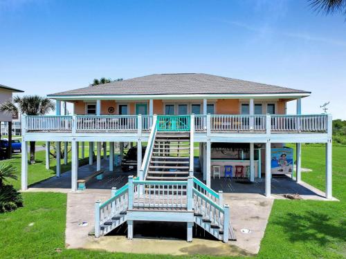 a house with a deck and stairs in front of it at Pelicans and Palms home in Crystal Beach