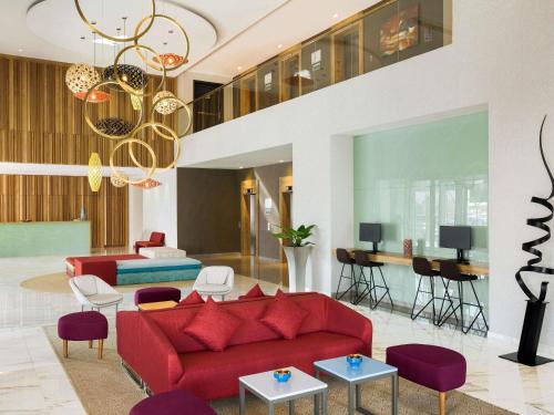 a living room with a red couch and purple chairs at Adagio Jeddah City Center in Jeddah