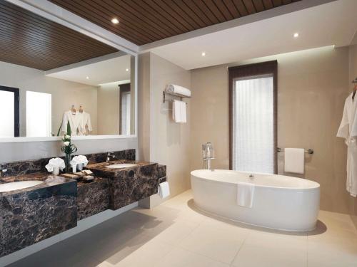 a bathroom with two sinks and a large tub at Movenpick Resort & Spa Boracay in Boracay