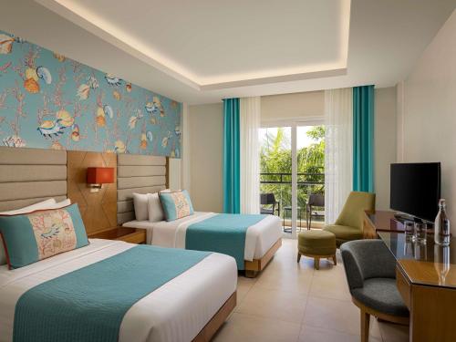 a hotel room with two beds and a desk at Movenpick Resort & Spa Boracay in Boracay