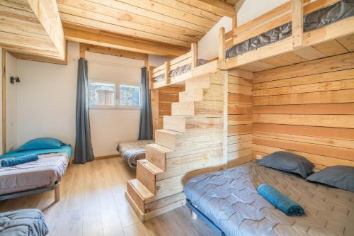 a bedroom with two bunk beds and wooden walls at Le Mûrier - Grospierres in Grospierres