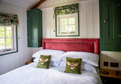 a bedroom with a red headboard and two pillows on a bed at Melbury Hut in Shaftesbury