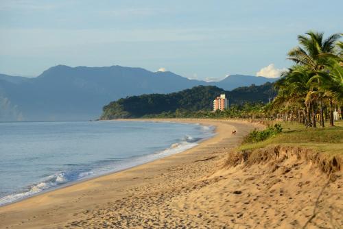 a sandy beach with palm trees and the ocean at Brisa Hotel in Caraguatatuba