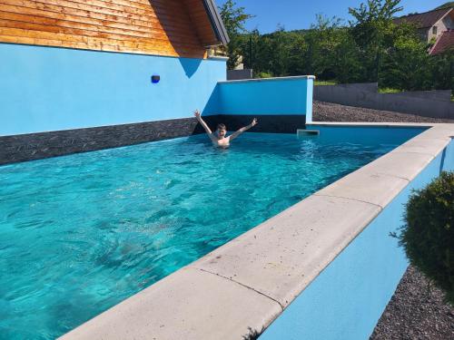 a man in a pool with his arms in the water at All4you Chalet Călimănești in Jiblea Veche