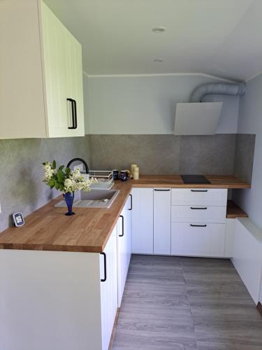 a kitchen with white cabinets and a vase of flowers on a counter at Amber in Ragaciems