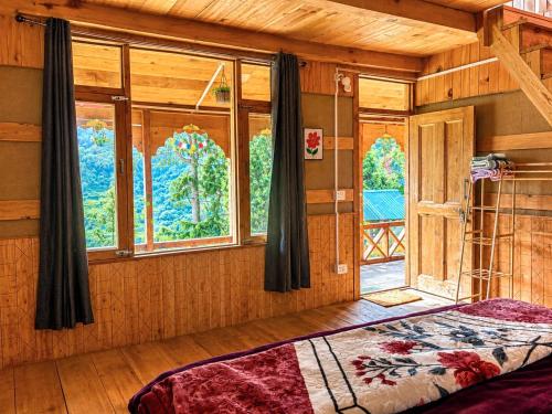 a bedroom with a bed in a room with windows at Kabir's Chalet Shangarh in Shangarh