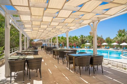 a patio with tables and chairs next to a swimming pool at Ladonia Hotels Zemda in Gümüşlük